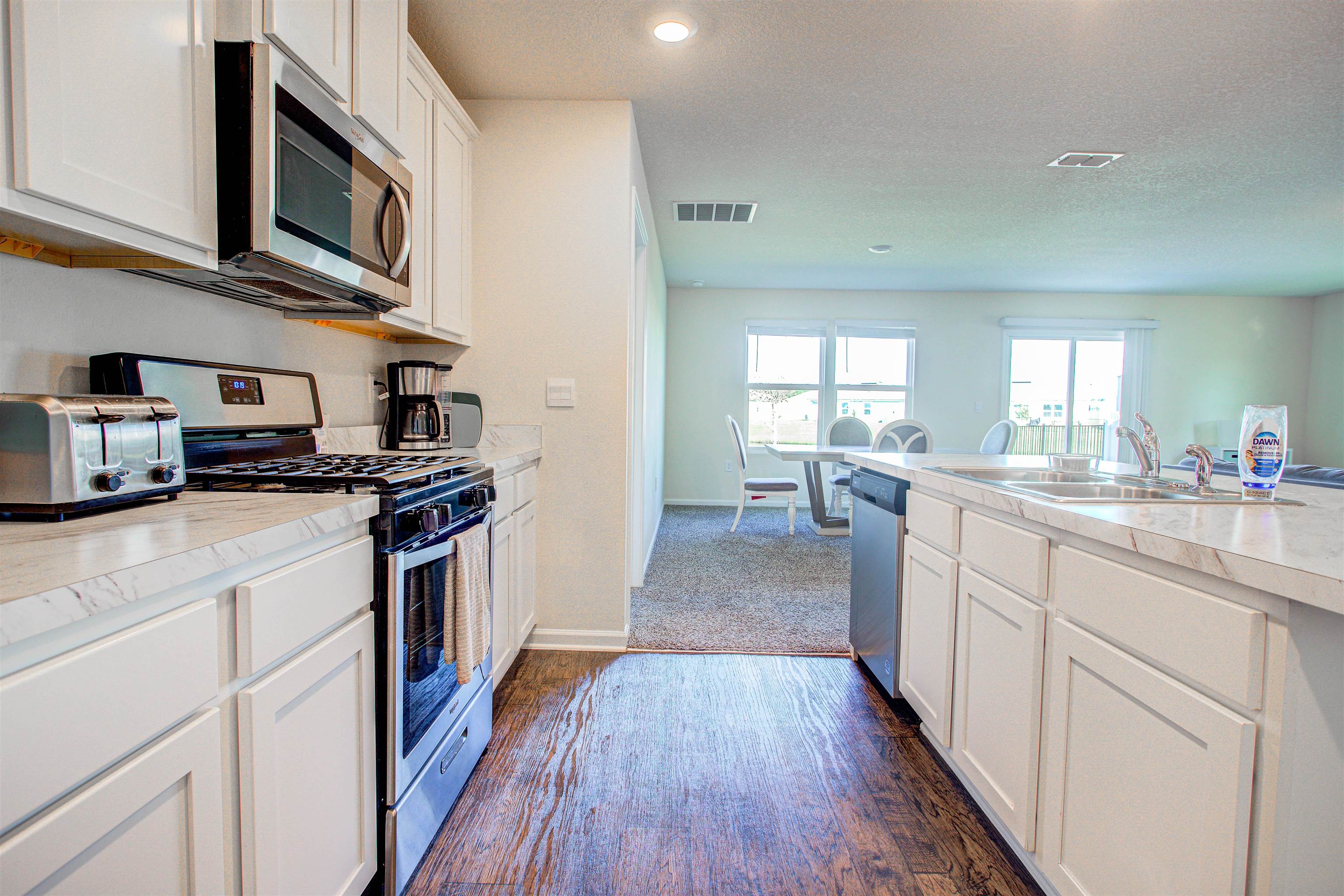 108 Albacete Road St. Augustine, FL 32084 - Photo 23 of 37 a kitchen with stainless steel appliances a stove top oven a sink a refrigerator white cabinets and wooden floor
