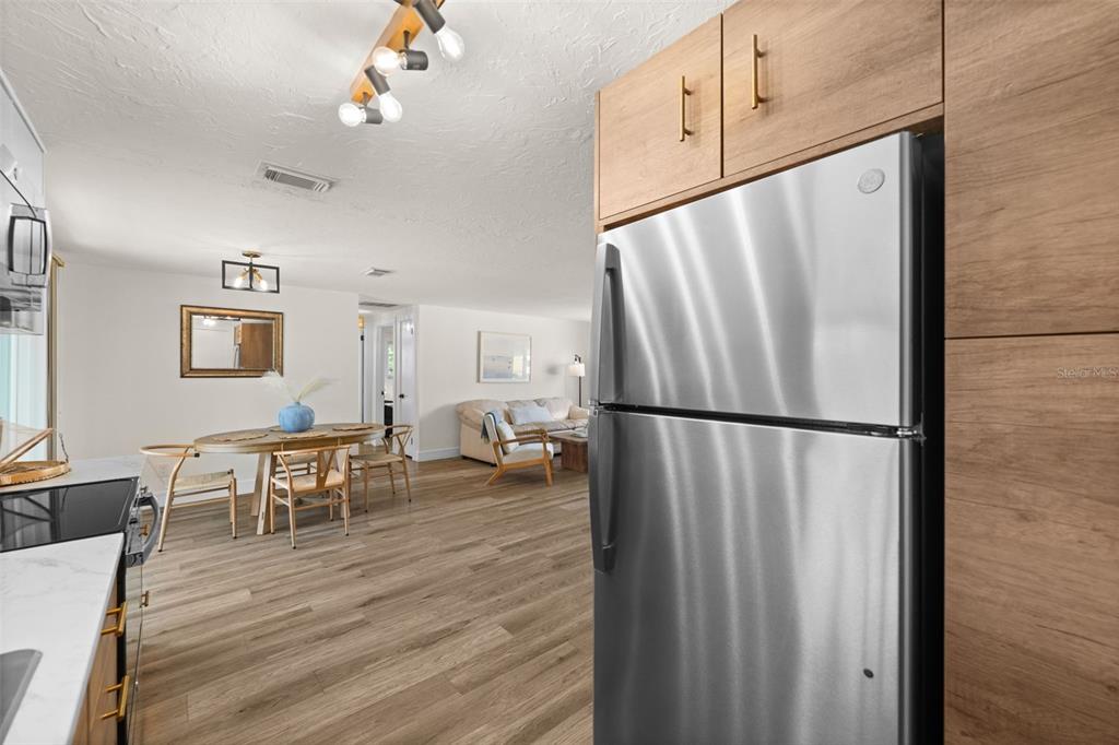 219 Coral Road Venice, FL 34293 - Photo 12 of 24 a kitchen with stainless steel appliances granite countertop a refrigerator a stove a dining table and chairs with wooden floor