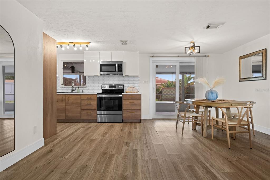 219 Coral Road Venice, FL 34293 - Photo 8 of 24 a kitchen with stainless steel appliances granite countertop a stove top oven a sink dishwasher a dining table and chairs with wooden floor