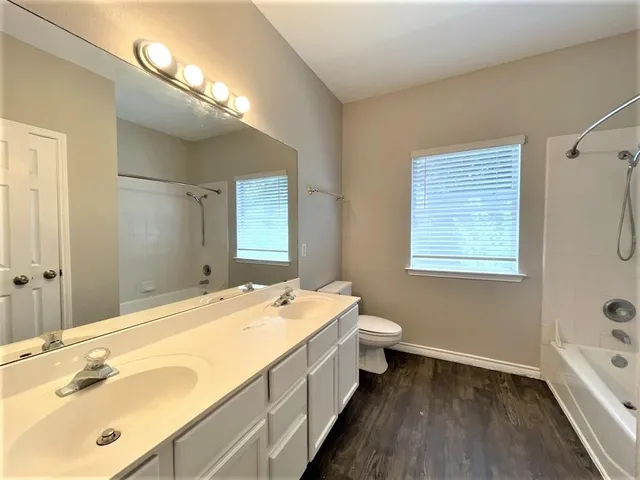 a bathroom with a double vanity sink toilet a mirror and shower