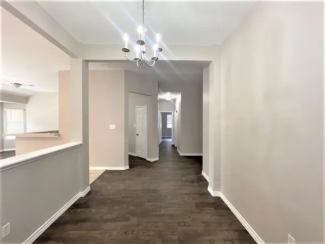 a view of a hallway with wooden floor and chandelier