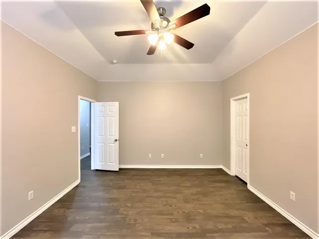 an empty room with closet and a ceiling fan