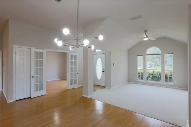 a view of an empty room with window and wooden floor