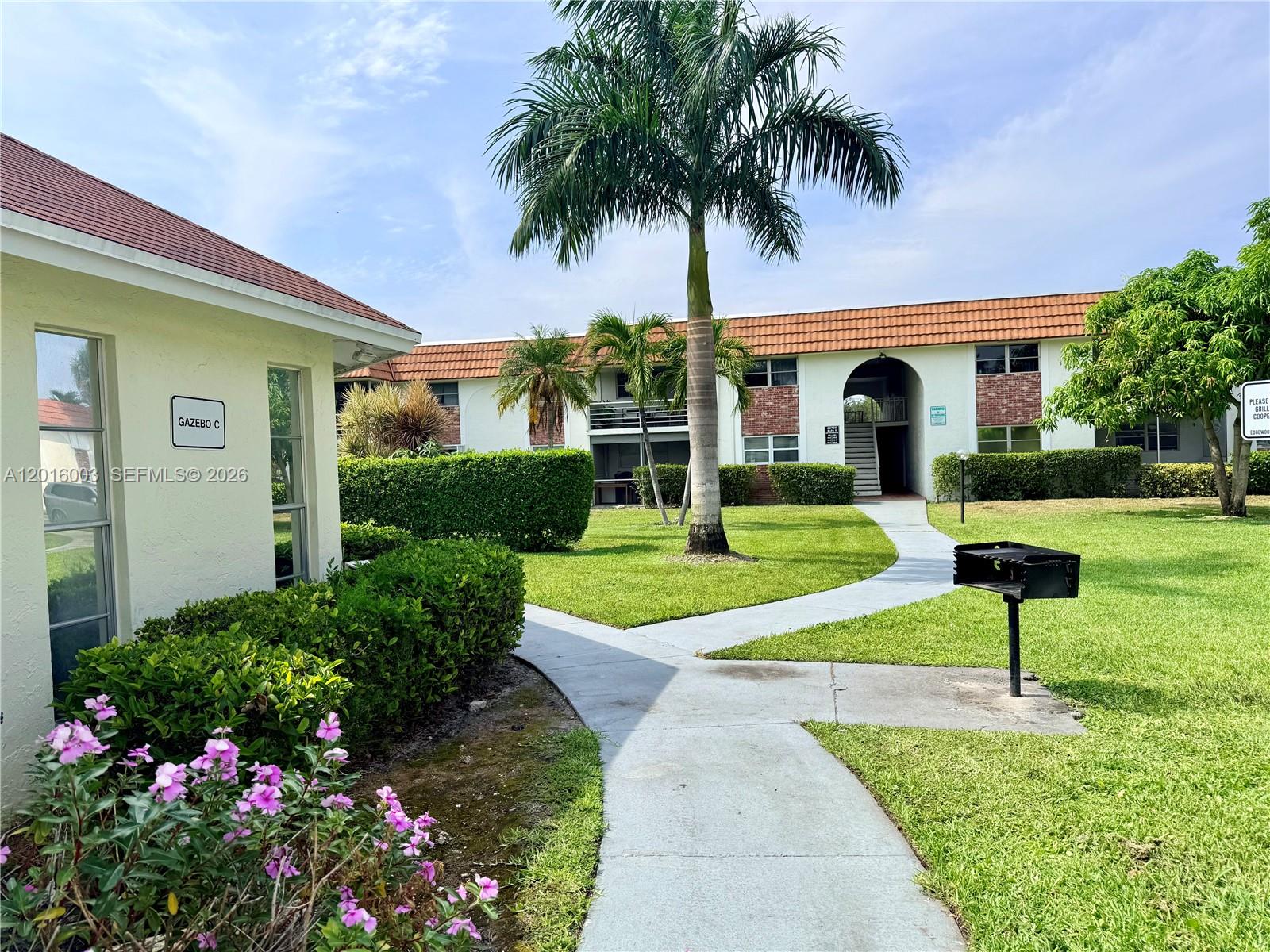 22805 Southwest 66th Avenue, Unit 208 Boca Raton, FL 33428 - Photo 4 of 28 a front view of a house with a yard and potted plants