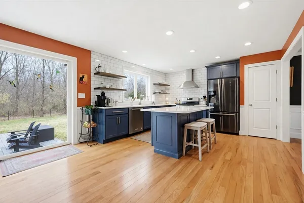 a kitchen with stainless steel appliances kitchen island granite countertop a refrigerator a sink a stove and a wooden cabinets