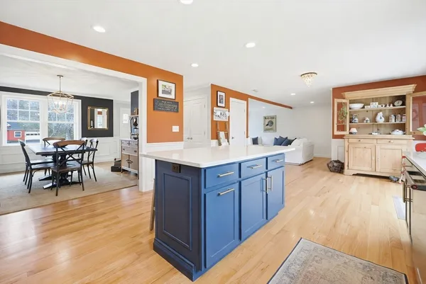 a large kitchen with stainless steel appliances granite countertop a living room and couches with wooden floor