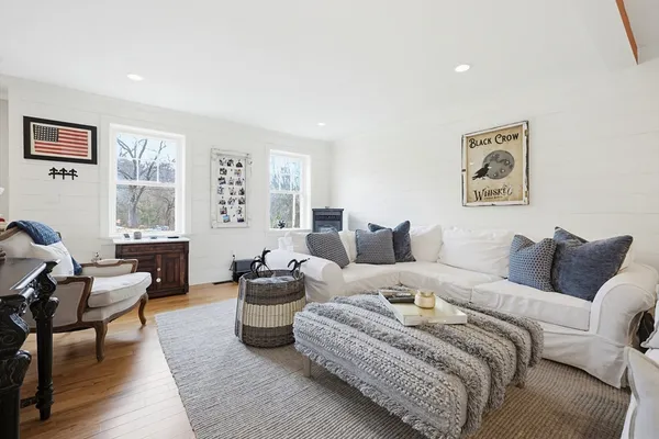 a living room with furniture large window and wooden floor