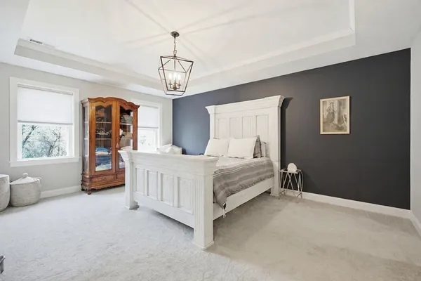 a bedroom with a large bed a chandelier and dresser