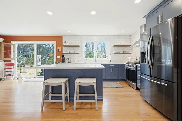 a kitchen with stainless steel appliances granite countertop a stove refrigerator and a large window with wooden floor