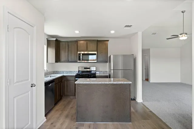 a kitchen with stainless steel appliances granite countertop a refrigerator a sink a stove and cabinets