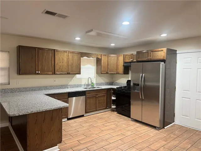 a kitchen with stainless steel appliances granite countertop a refrigerator a sink a stove a microwave and island