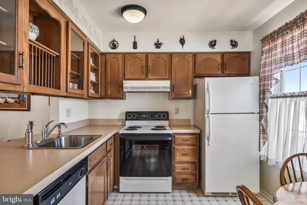 a kitchen with stainless steel appliances granite countertop a refrigerator a stove and a sink with wooden cabinets