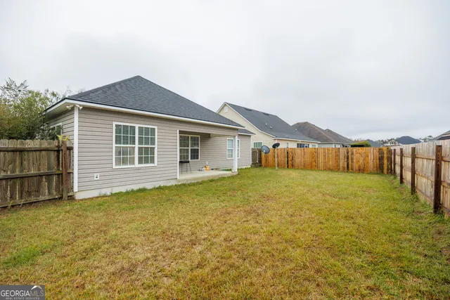 a view of a house with backyard and wooden fence