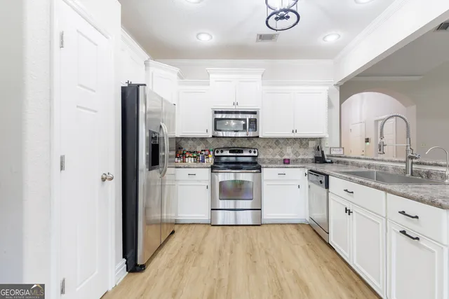 a kitchen with granite countertop a refrigerator stove and sink