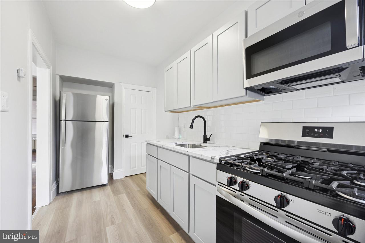 5818 Addison Street Philadelphia, PA 19143 - Photo 4 of 11 a kitchen with stainless steel appliances granite countertop a stove and a microwave