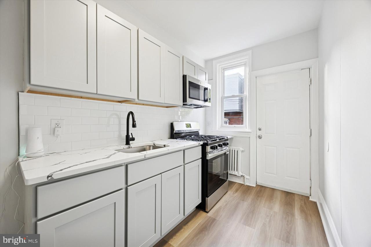 5818 Addison Street Philadelphia, PA 19143 - Photo 5 of 11 a kitchen with stainless steel appliances granite countertop a sink stove and refrigerator