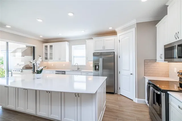 a large white kitchen with kitchen island lots of counter space a sink appliances and cabinets