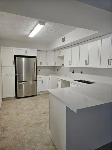 a kitchen with stainless steel appliances a refrigerator sink and white cabinets
