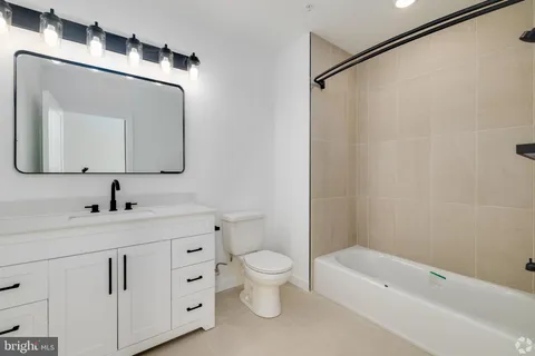 a bathroom with a toilet a sink a tub and mirror