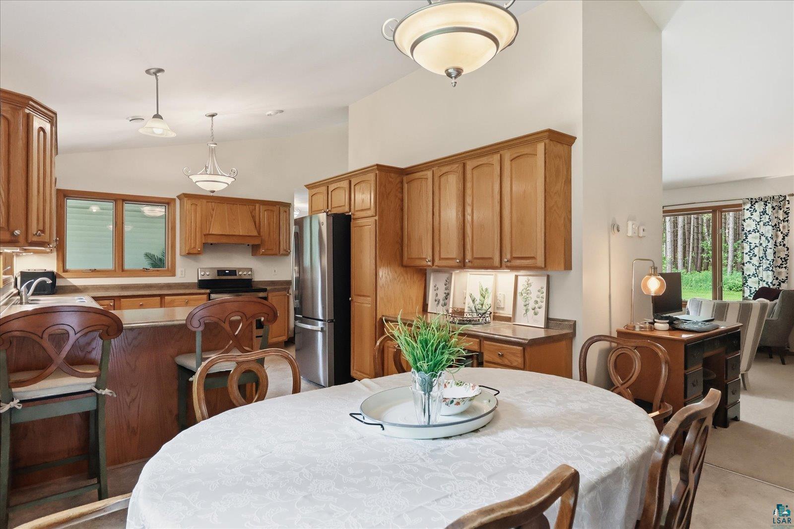 41 East Stark Road Esko, MN 55733 - Photo 7 of 19 Open-concept kitchen and dining area featuring warm wood cabinetry, stainless steel appliances, a breakfast bar, and pendant lighting