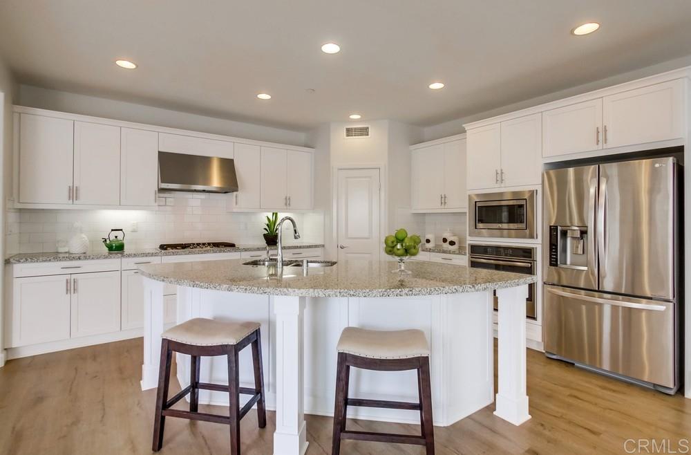 13413 Red Oak Way San Diego, CA 92130 - Photo 9 of 25 a kitchen with white cabinets and stainless steel appliances