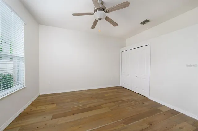 an empty room with a window and ceiling fan