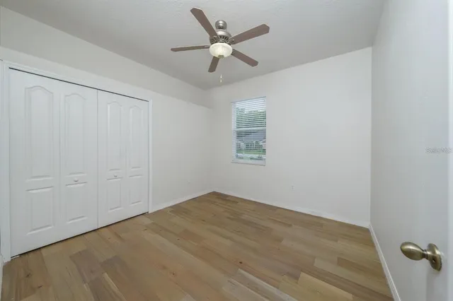 an empty room with ceiling fan and window
