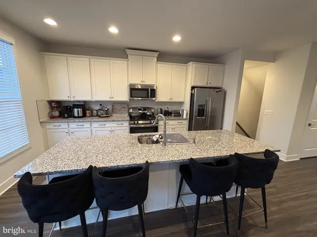 a kitchen with stainless steel appliances granite countertop a table chairs sink refrigerator and microwave
