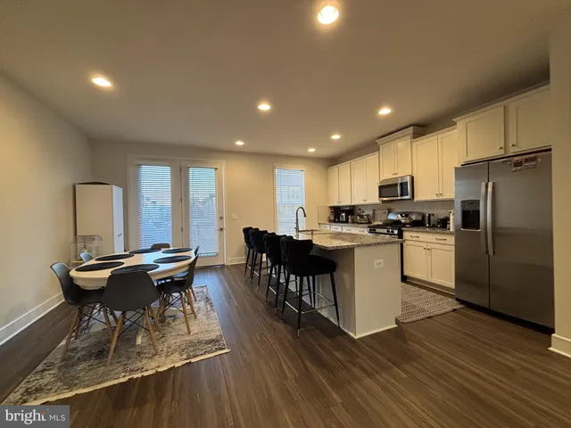 a kitchen with a table chairs a sink dishwasher refrigerator and cabinets
