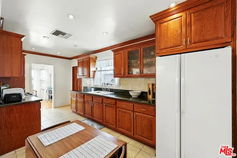 a large kitchen with stainless steel appliances granite countertop a refrigerator and wooden cabinets