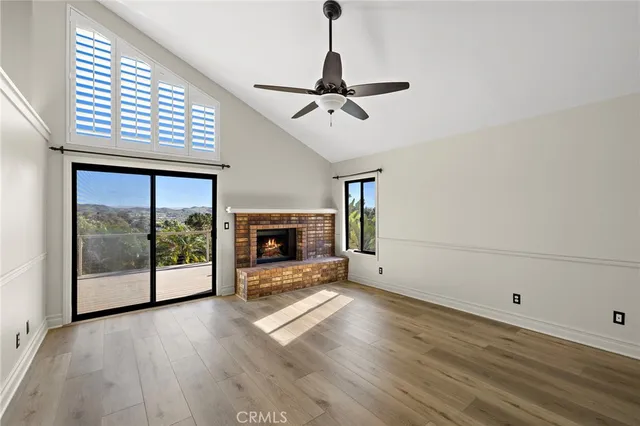 an empty room with wooden floor fireplace and windows