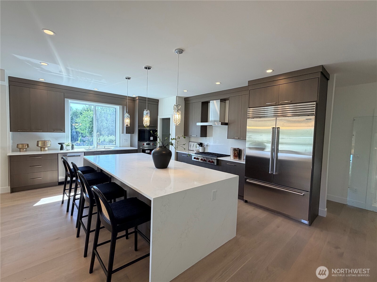 4305 Northeast 26th Court Renton, WA 98059 - Photo 8 of 40 a kitchen with stainless steel appliances kitchen island granite countertop a table chairs sink and white cabinets