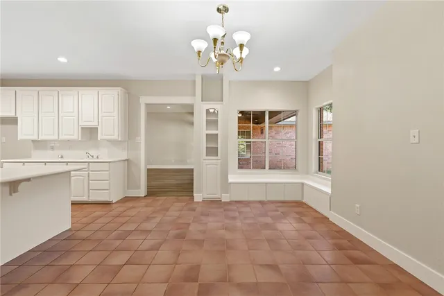 a large white kitchen with kitchen island a chandelier stainless steel appliances cabinets and a counter top space