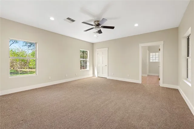 a view of a livingroom with a ceiling fan & windows