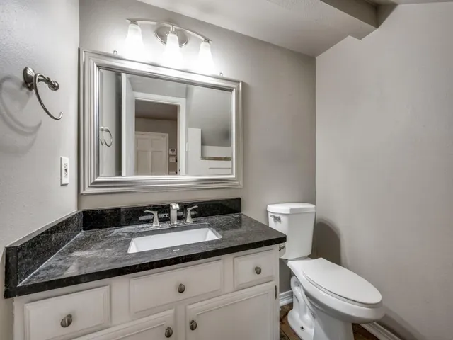 a bathroom with a granite countertop toilet a sink and mirror