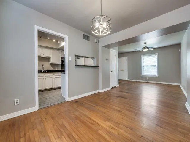 a view of a big room with wooden floor and kitchen view