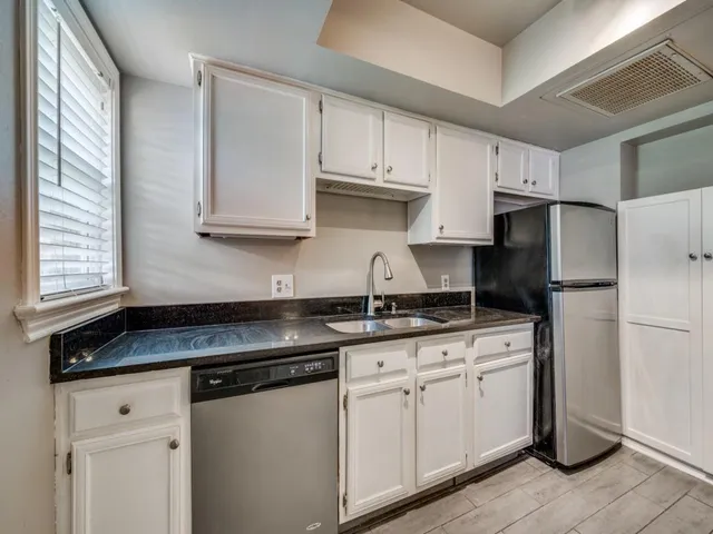 a kitchen with granite countertop white cabinets and white appliances