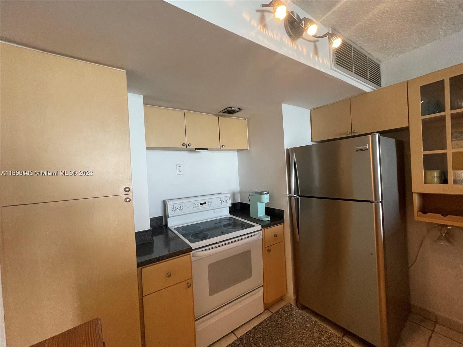 9273 Collins Avenue, Unit 811 Surfside, FL 33154 - Photo 13 of 25 a kitchen with a refrigerator sink stove and cabinets