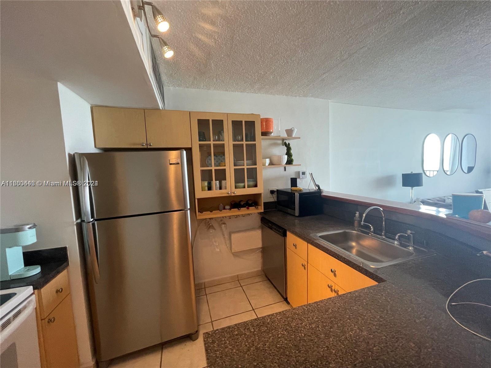 9273 Collins Avenue, Unit 811 Surfside, FL 33154 - Photo 14 of 25 a kitchen with stainless steel appliances granite countertop a refrigerator a sink a stove a washer dryer and a refrigerator