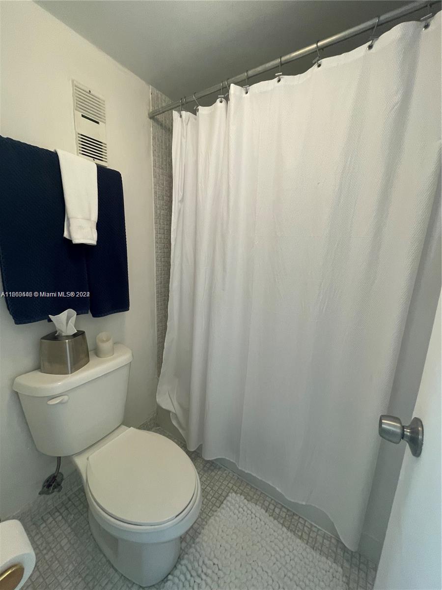 9273 Collins Avenue, Unit 811 Surfside, FL 33154 - Photo 16 of 25 a bathroom with a toilet and a shower curtain