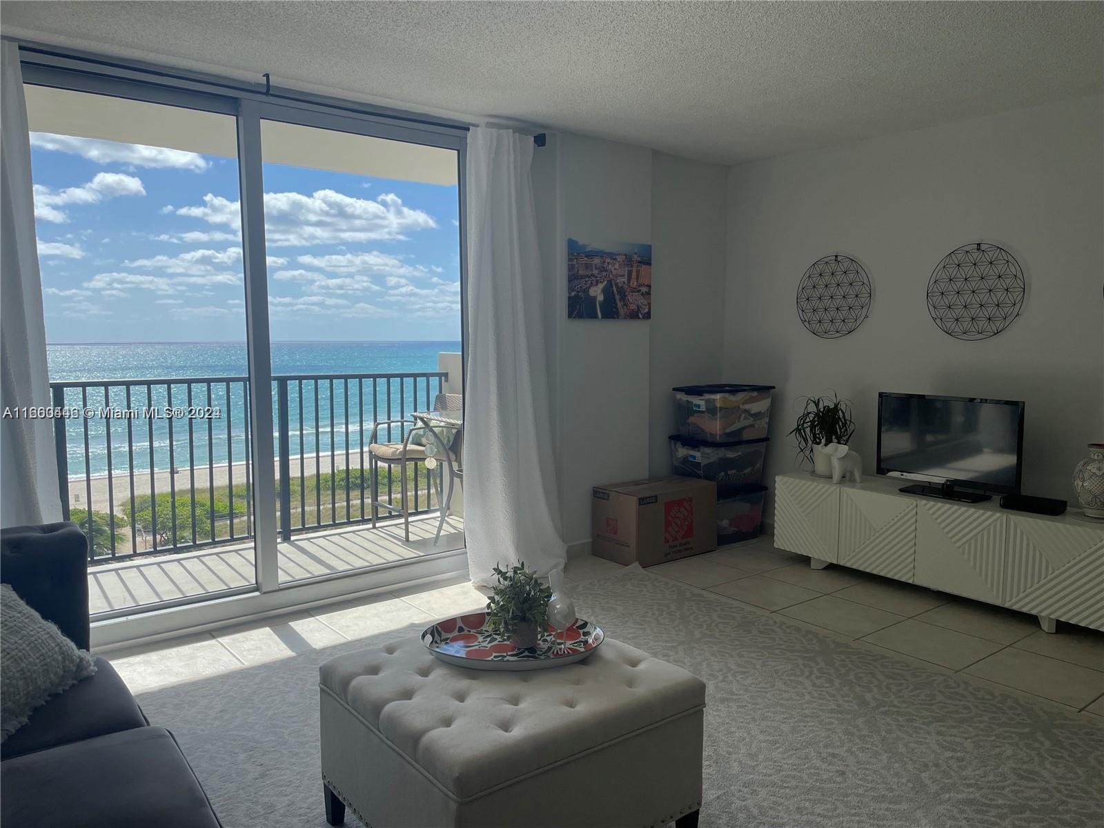 9273 Collins Avenue, Unit 811 Surfside, FL 33154 - Photo 3 of 25 a living room with furniture large window and a flat screen tv