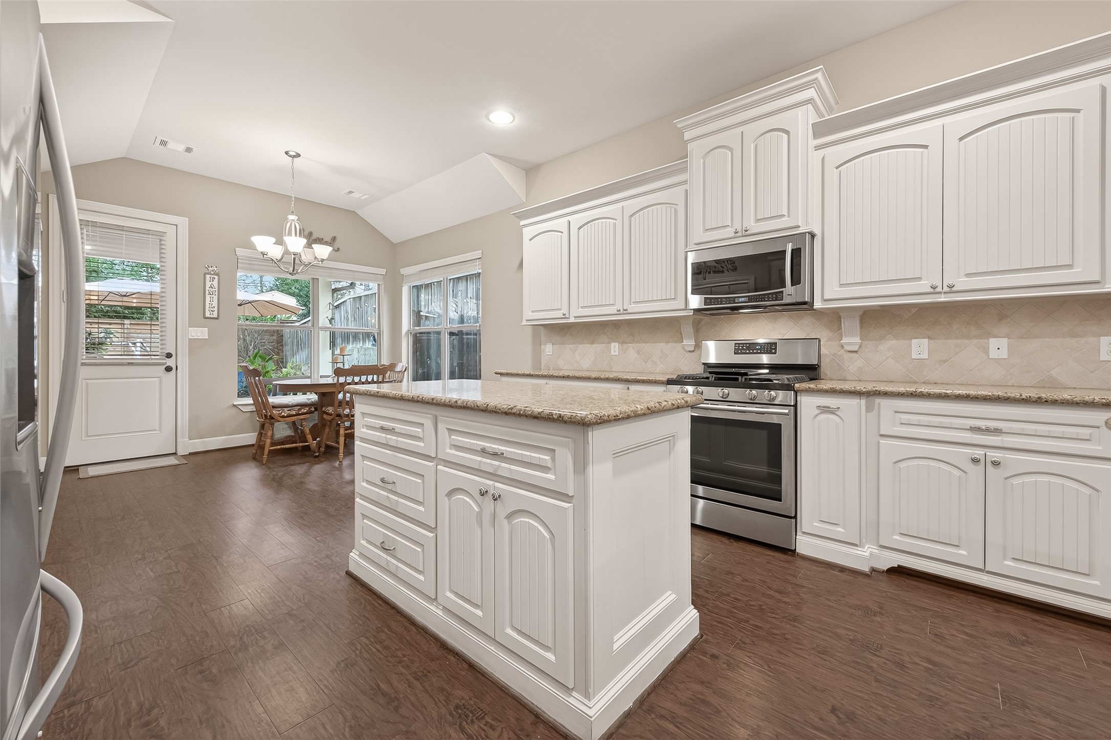 112 Timberside Drive Conroe, TX 77304 - Photo 13 of 50 a kitchen with stainless steel appliances granite countertop a stove top oven a sink dishwasher and white cabinets with wooden floor