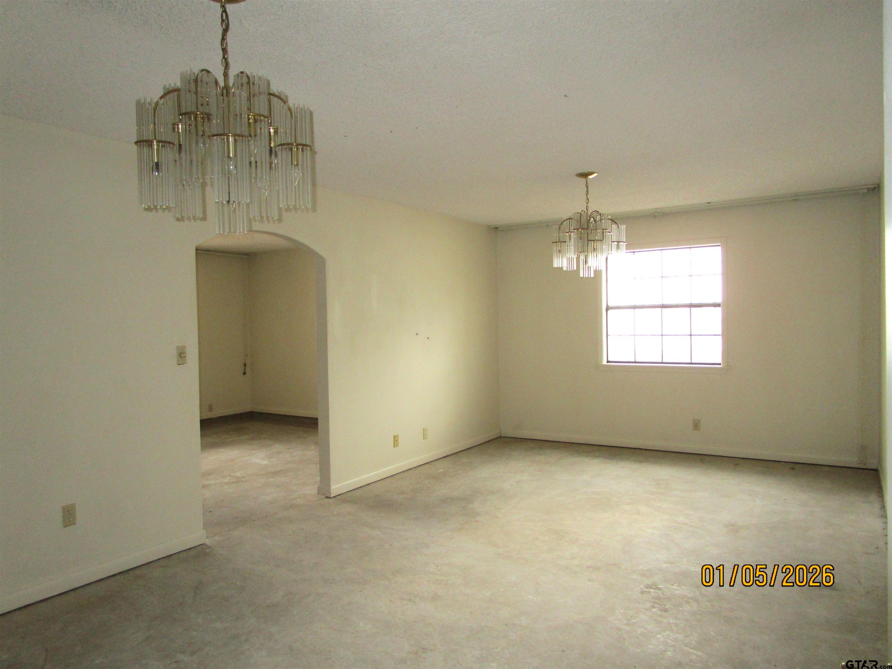 1317 South Butler Avenue Tyler, TX 75701 - Photo 3 of 13 an empty room with a windows and chandelier