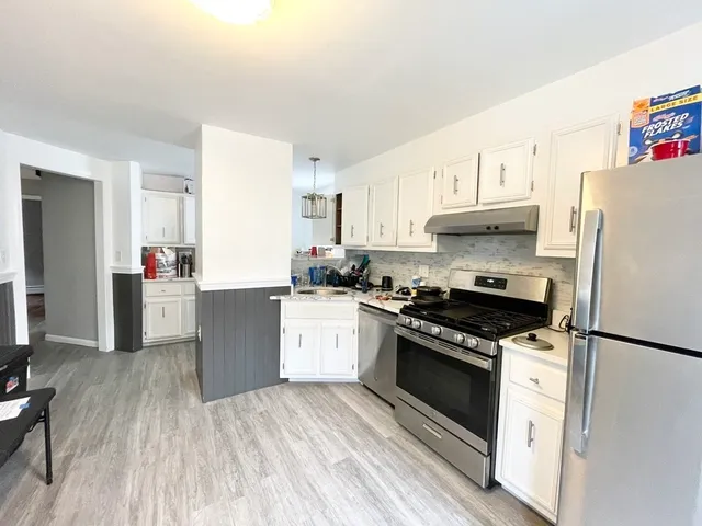a kitchen with granite countertop a refrigerator stove top oven and sink