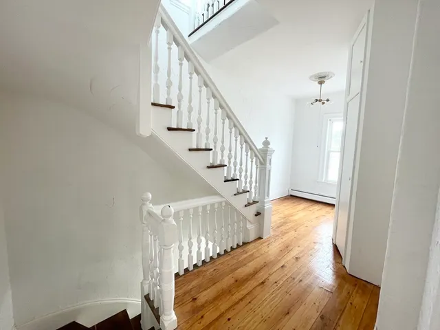 a view of staircase with wooden floor and white walls