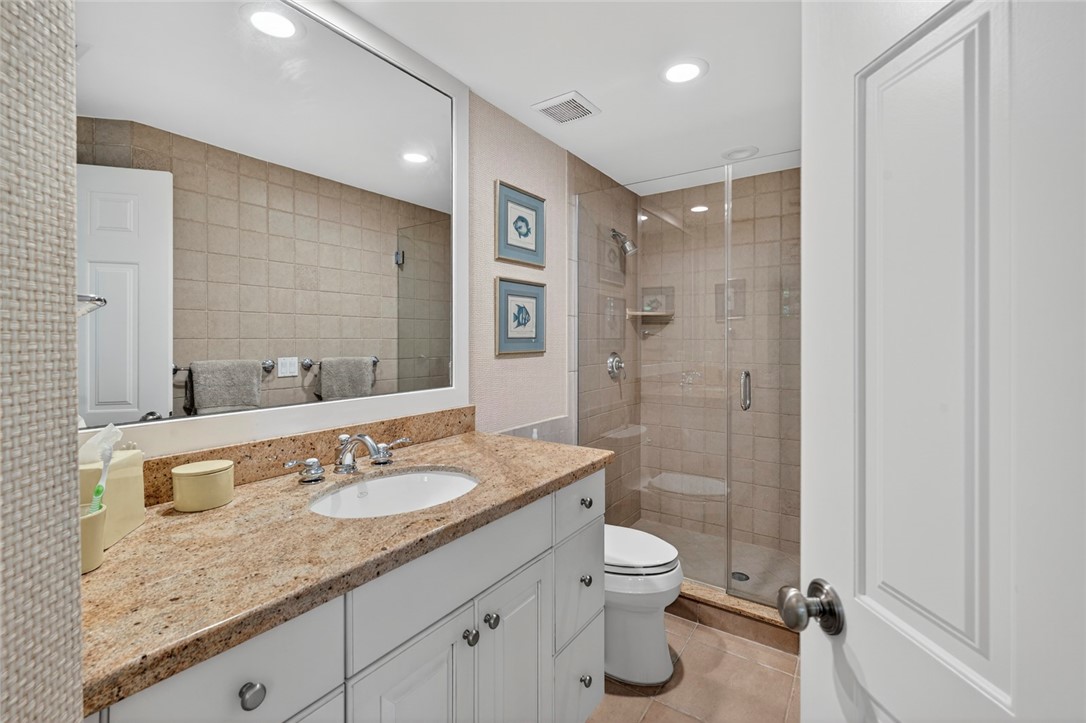 2525 Ocean Drive, Unit 3 Vero Beach, FL 32963 - Photo 20 of 36 a bathroom with a granite countertop sink a toilet a mirror and shower