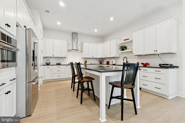 a kitchen with stainless steel appliances kitchen island granite countertop a refrigerator and white cabinets
