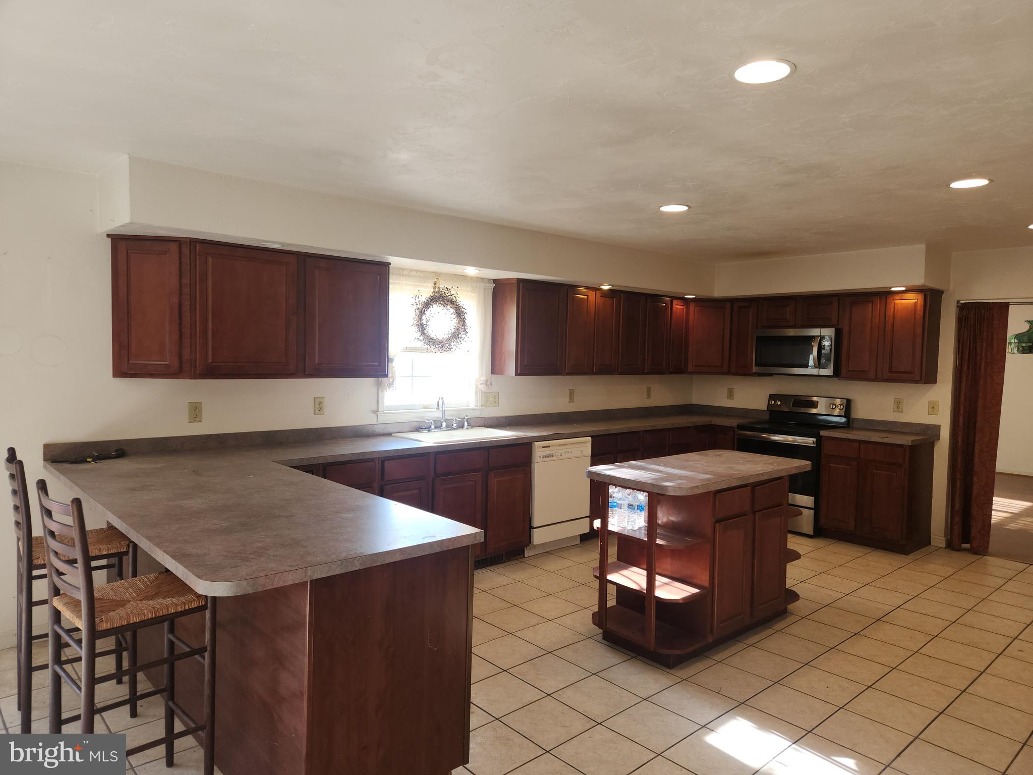 290 Locust Grove Road Bainbridge, PA 17502 - Photo 29 of 108 a kitchen with stainless steel appliances granite countertop a stove a sink dishwasher a microwave oven and a refrigerator with wooden cabinets