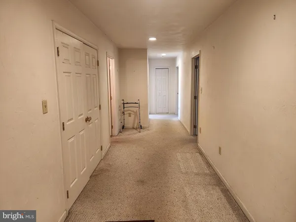 an empty room with a chandelier fan and windows