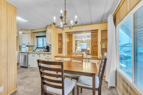 a view of a dining room with furniture a chandelier and kitchen view